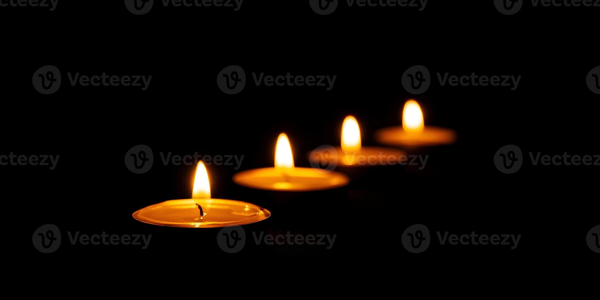 Four Burning Tea Light Candles in a Row Dark Background photo