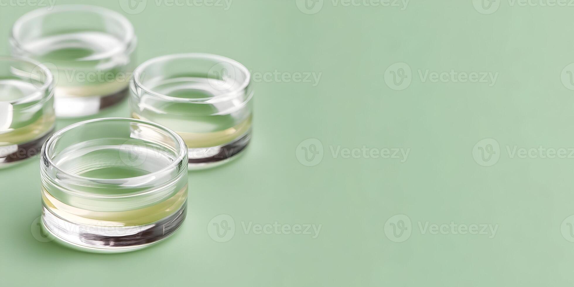Four Glass Containers with Light Yellow Liquid on Green Background photo