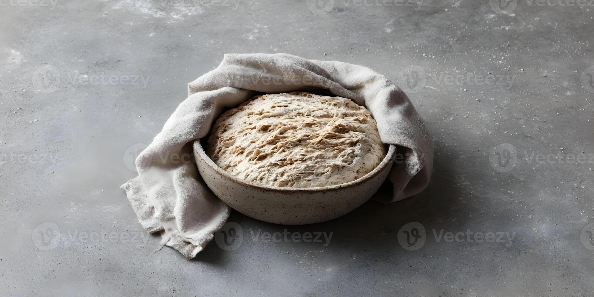 Artisan Bread Dough Rising in Bowl Covered with Linen Cloth on Concrete Background photo
