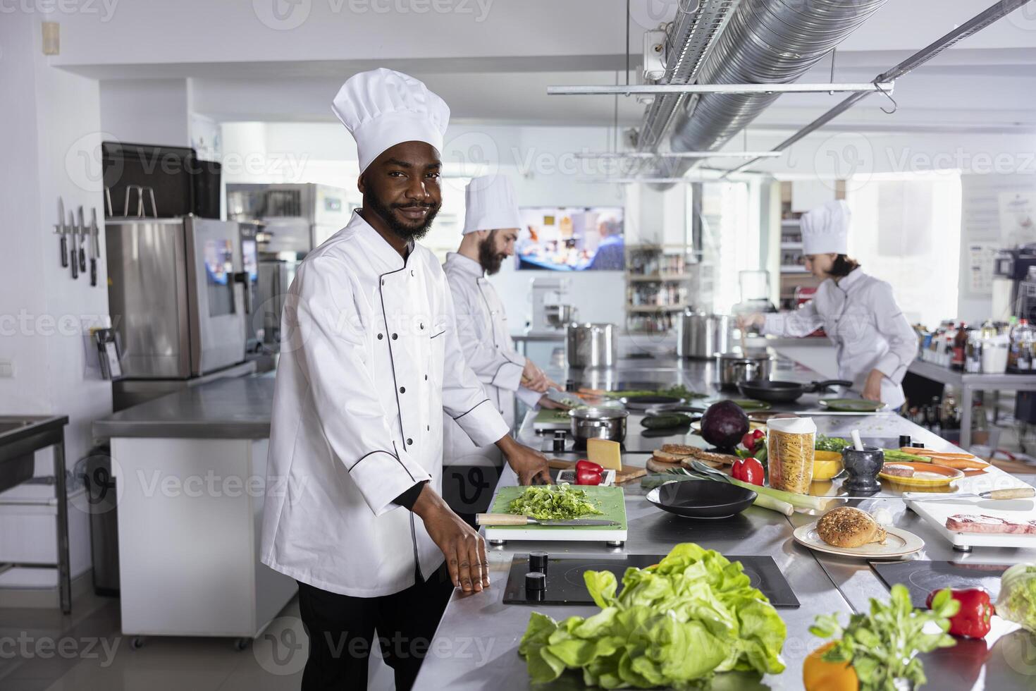 Black chef stands at a stainless steel kitchen counter and preparing ingredients for a gourmet meal dish, skillfully cooking flavorful food with precision and creativity. Delicious gastronomy. photo