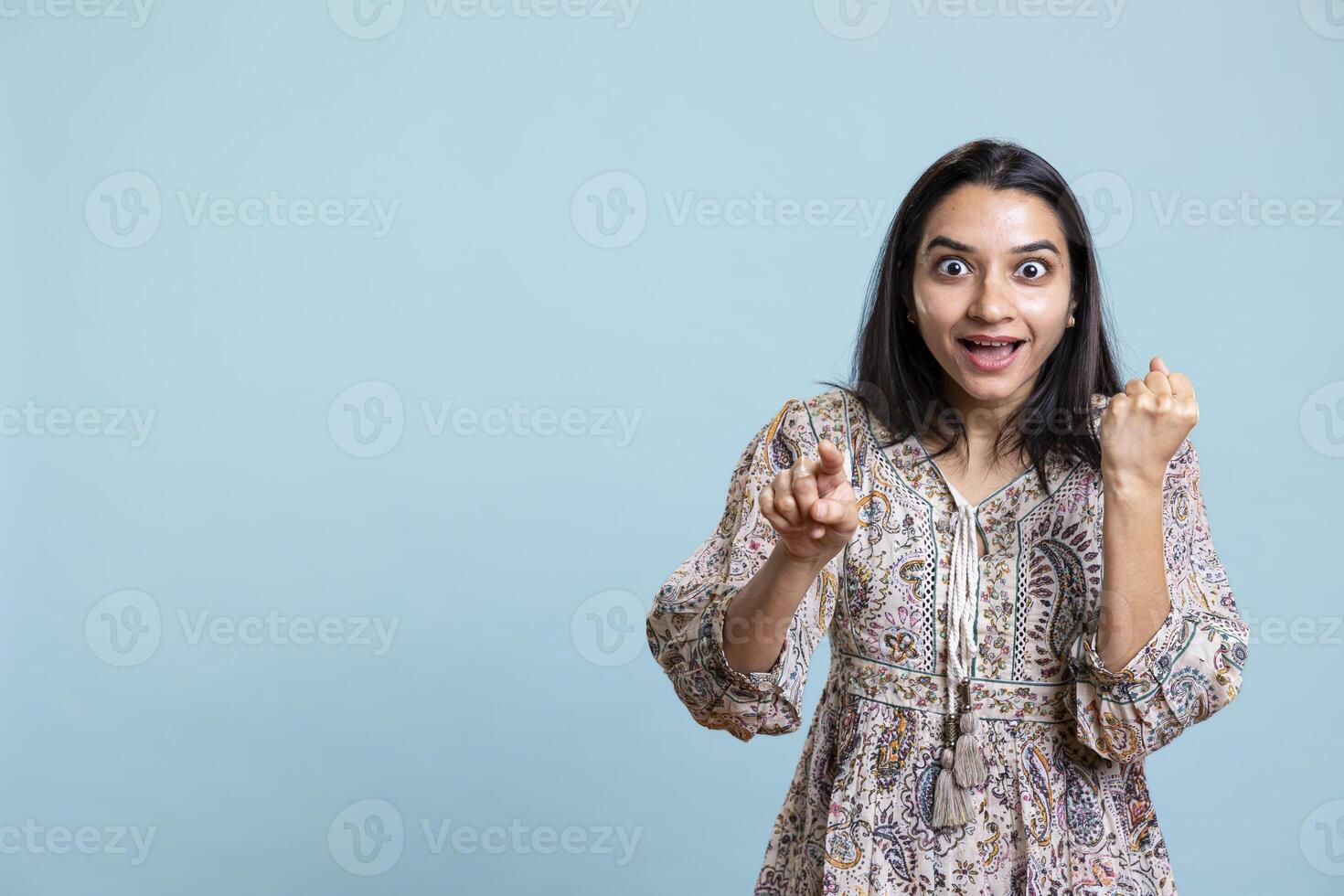 Ecstatic indian woman celebrating her win and achievement on camera, feeling proud and satisfied with the good news. Young adult being upbeat and overjoyed with her accomplishments. photo