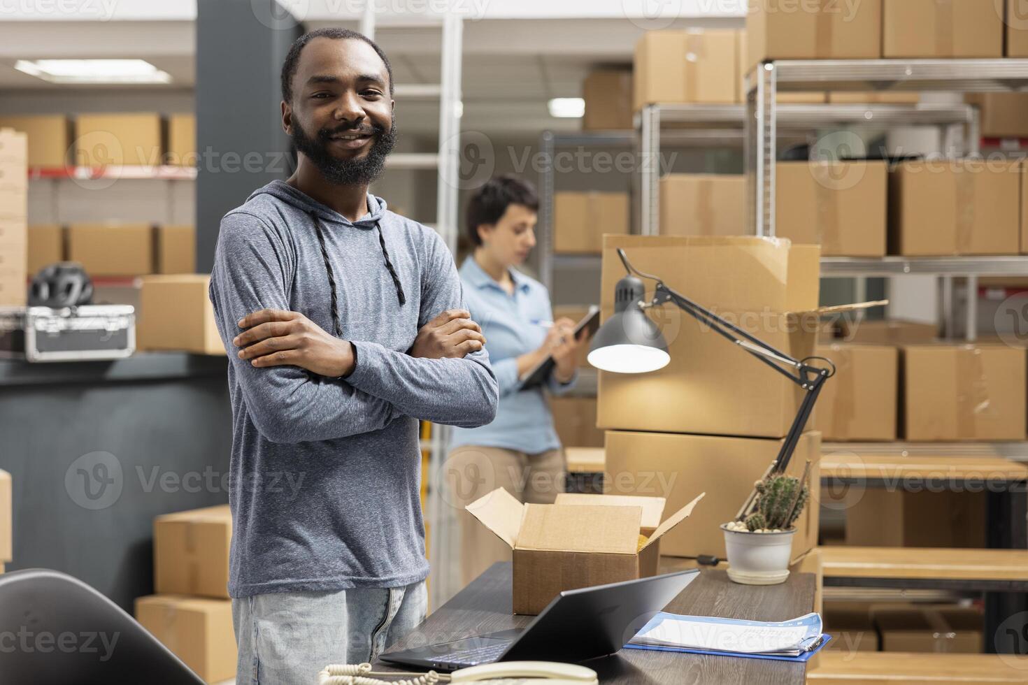 Business owner overseeing product handling and shipping systems inside a compact logistics center, retail activity. Black warehouse worker prepares boxes for shipment from supply room. photo