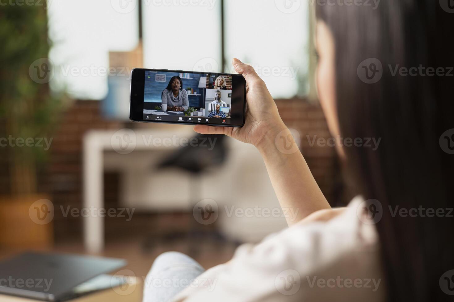 Female entrepreneur using cellphone for team conference, having digital briefing. Close up of device screen reflecting group collaboration, professional networking and remote teamwork. photo