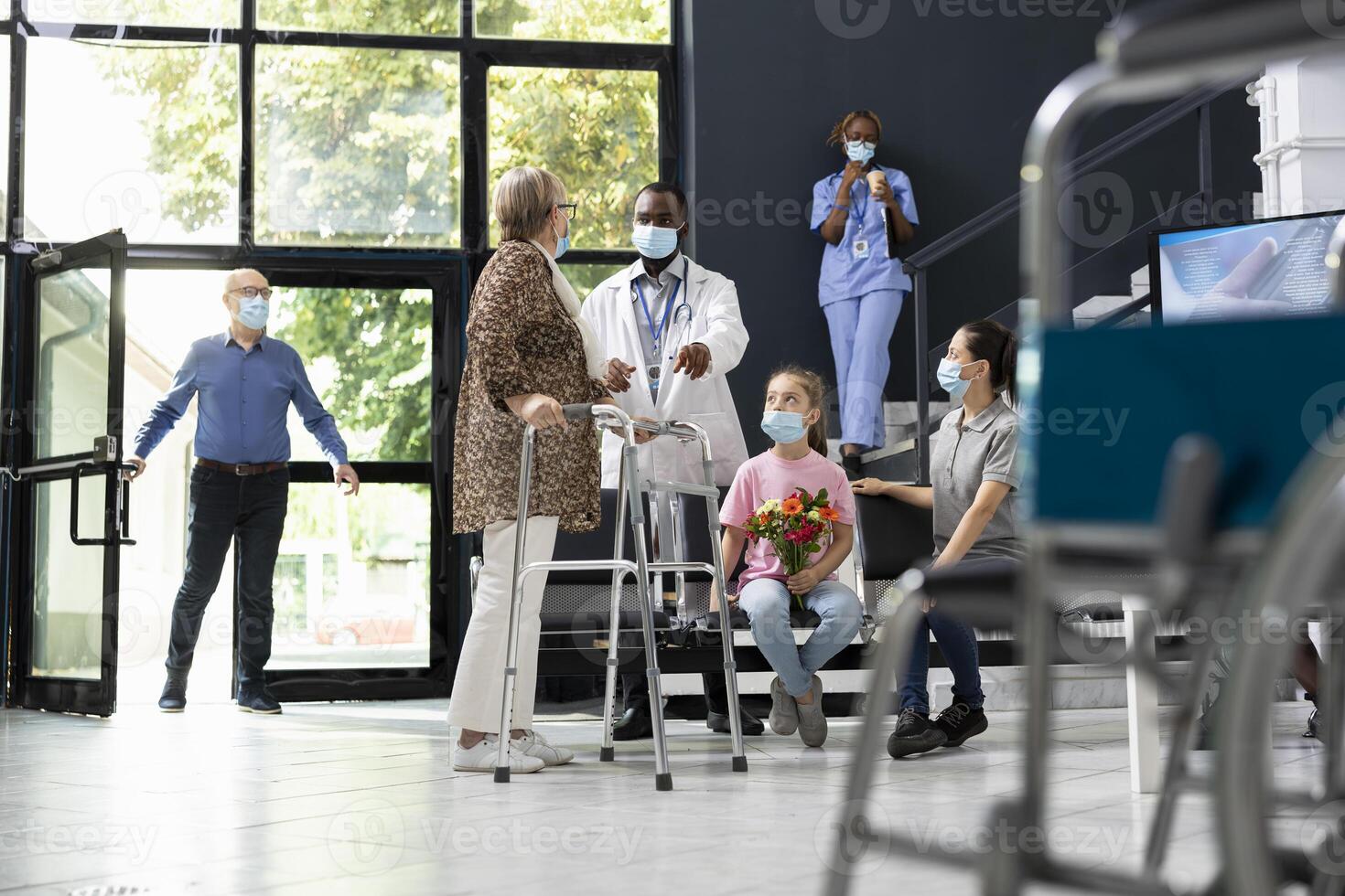 Little girl gives flowers to senior grandma with walking frame during patient visit, showing love and support while following safety rules, healthcare protection. Different generations at facility. photo