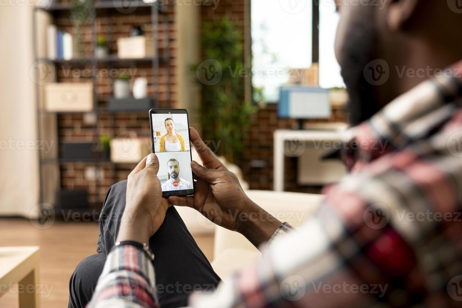 Self employed black man using cellphone for virtual meeting with potential investors. African american entrepreneur on call, seeking financial advice from team of caucasian accountants. photo