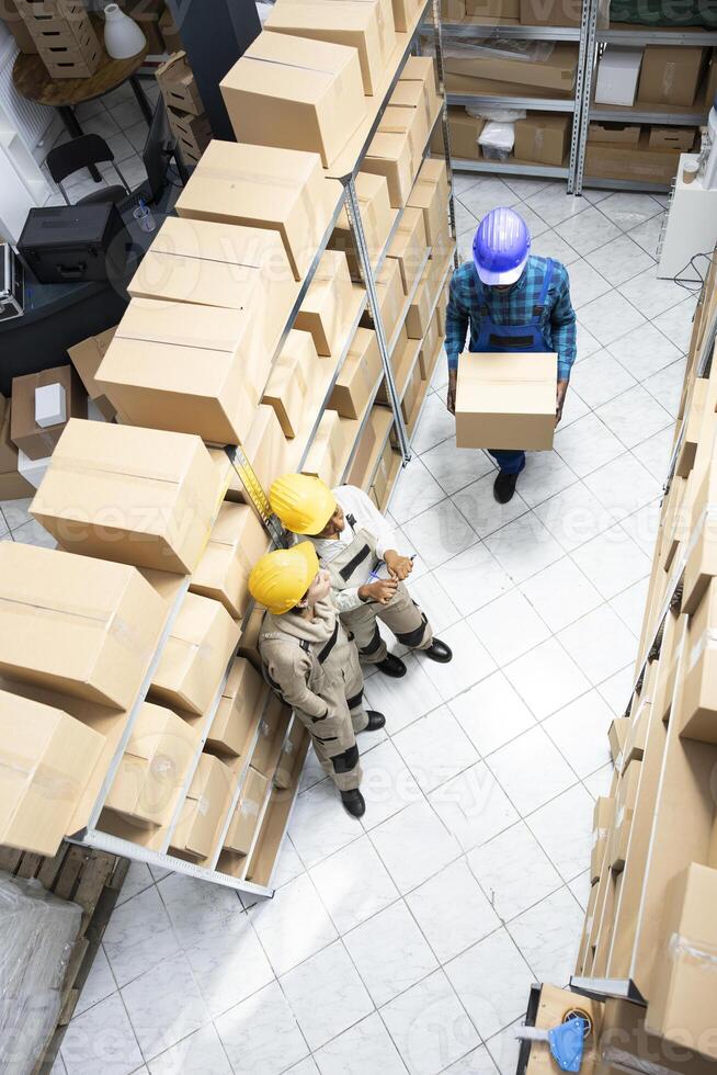Multiethnic staff in safety gear managing merchandise and logistics operations. Warehouse environment designed for effective inventory and transportation, distribution management. photo