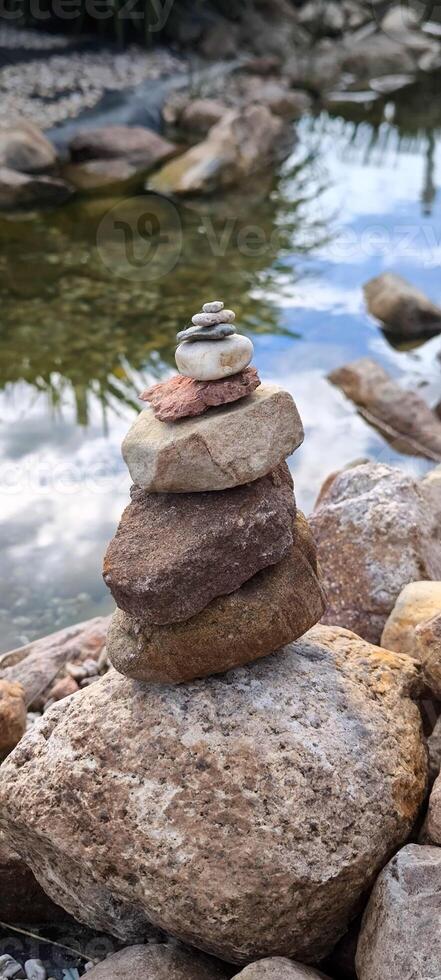 A pyramid made of stones on the shore of a pond photo