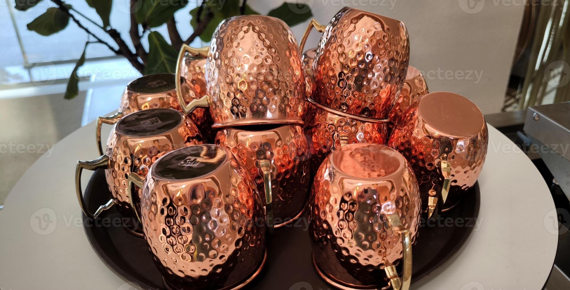 Shiny copper mugs stacked on a round tray photo