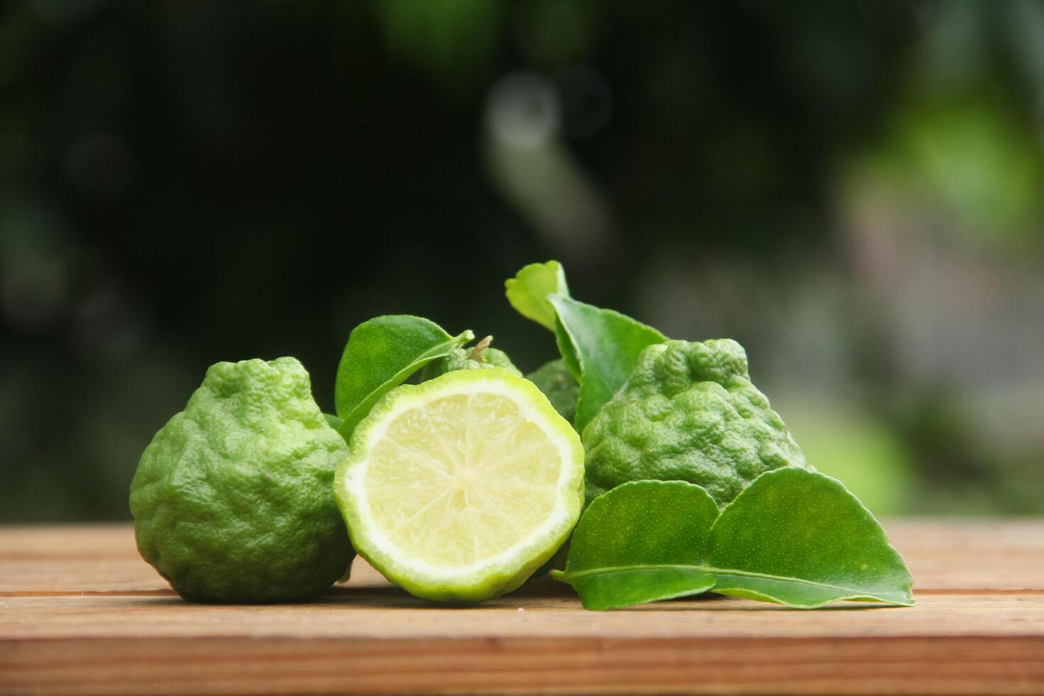 Fresh lime on wooden table with green leaves photo
