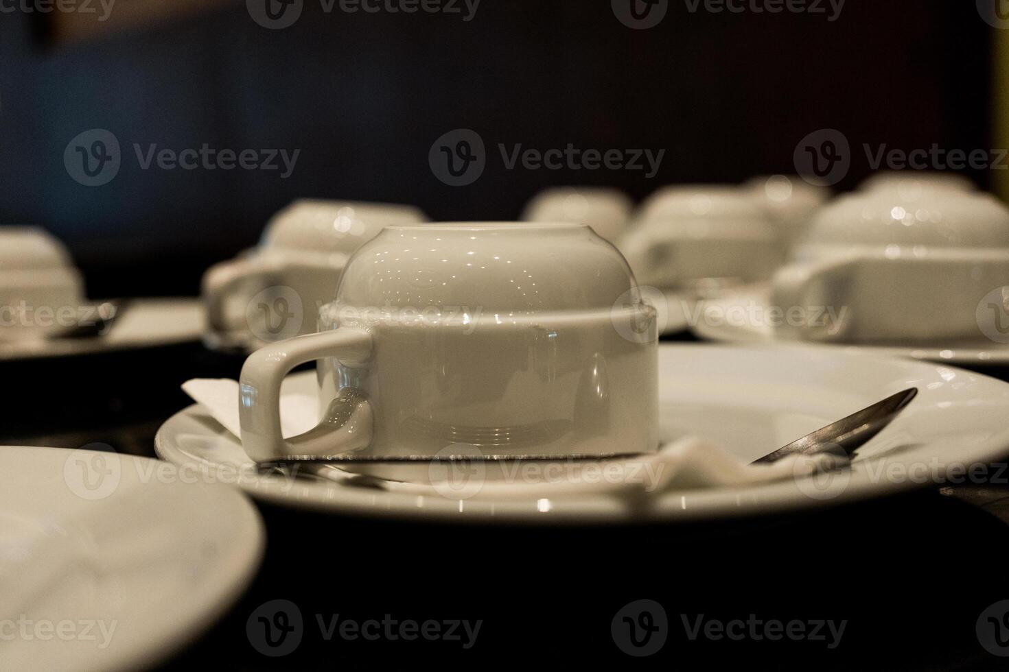 White coffee cups and saucers are placed upside down on table. photo