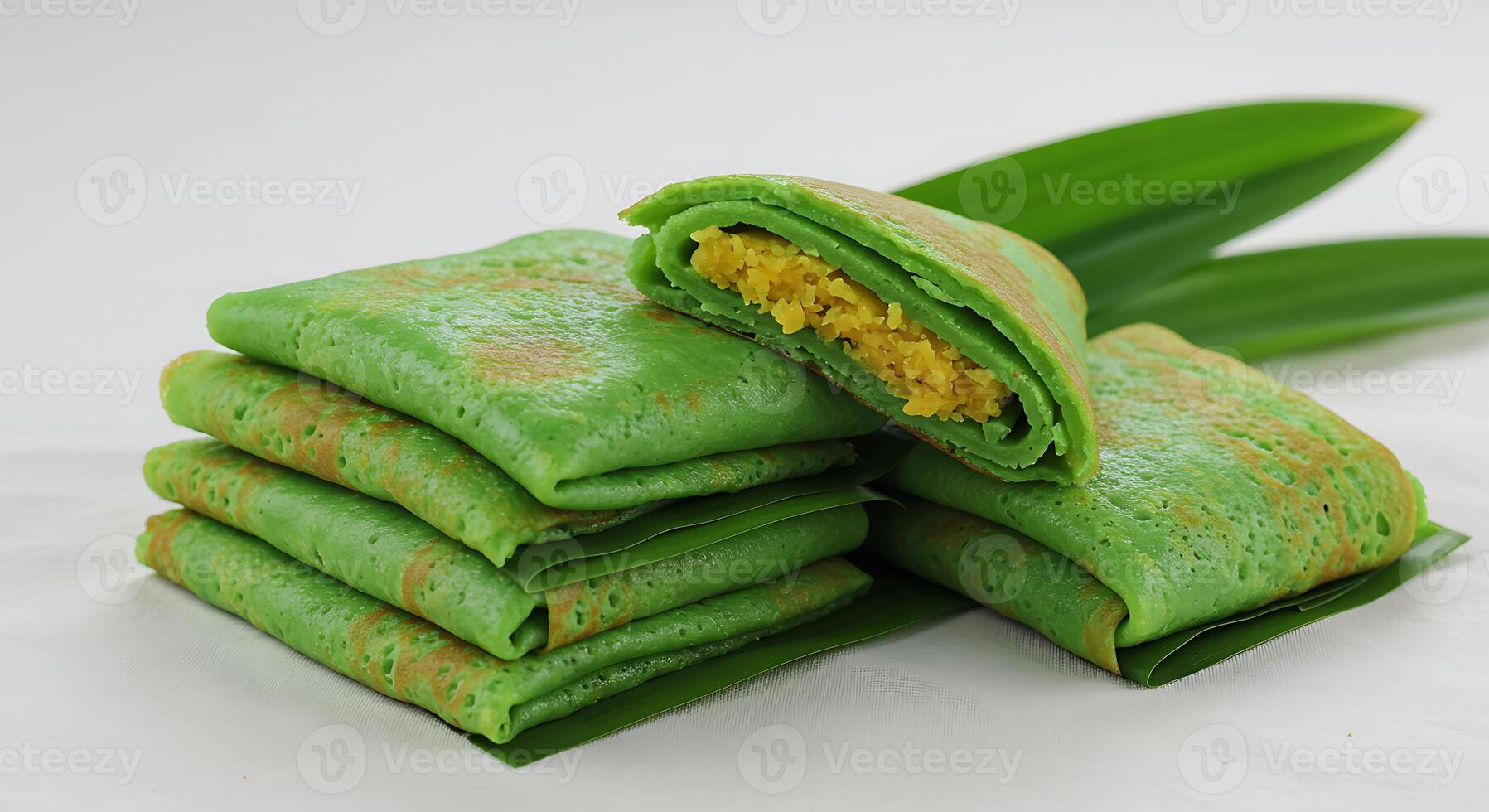 Close Up of Green Pancakes Filled with Yellow Filling and Fresh Leaves photo