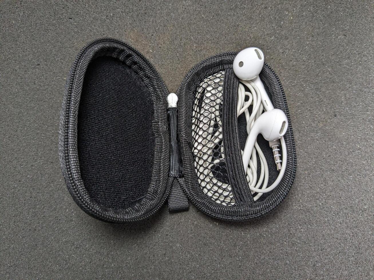 Open Earphone Case with White Earbuds on a Dark Gray Surface Closeup View photo