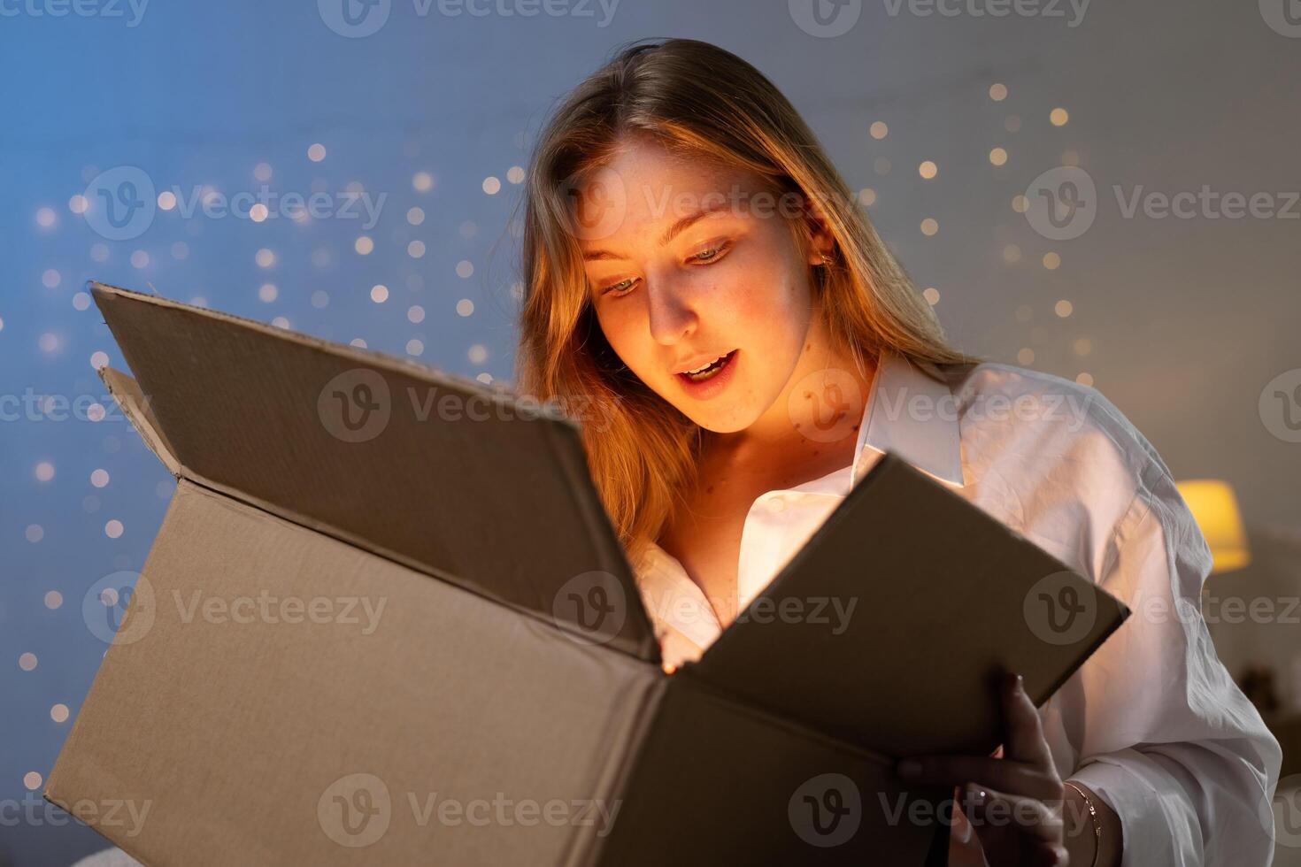 Amazed Young Woman Opening Glowing Parcel at Home Representing Unboxing Delivery and Online Shopping Joy photo