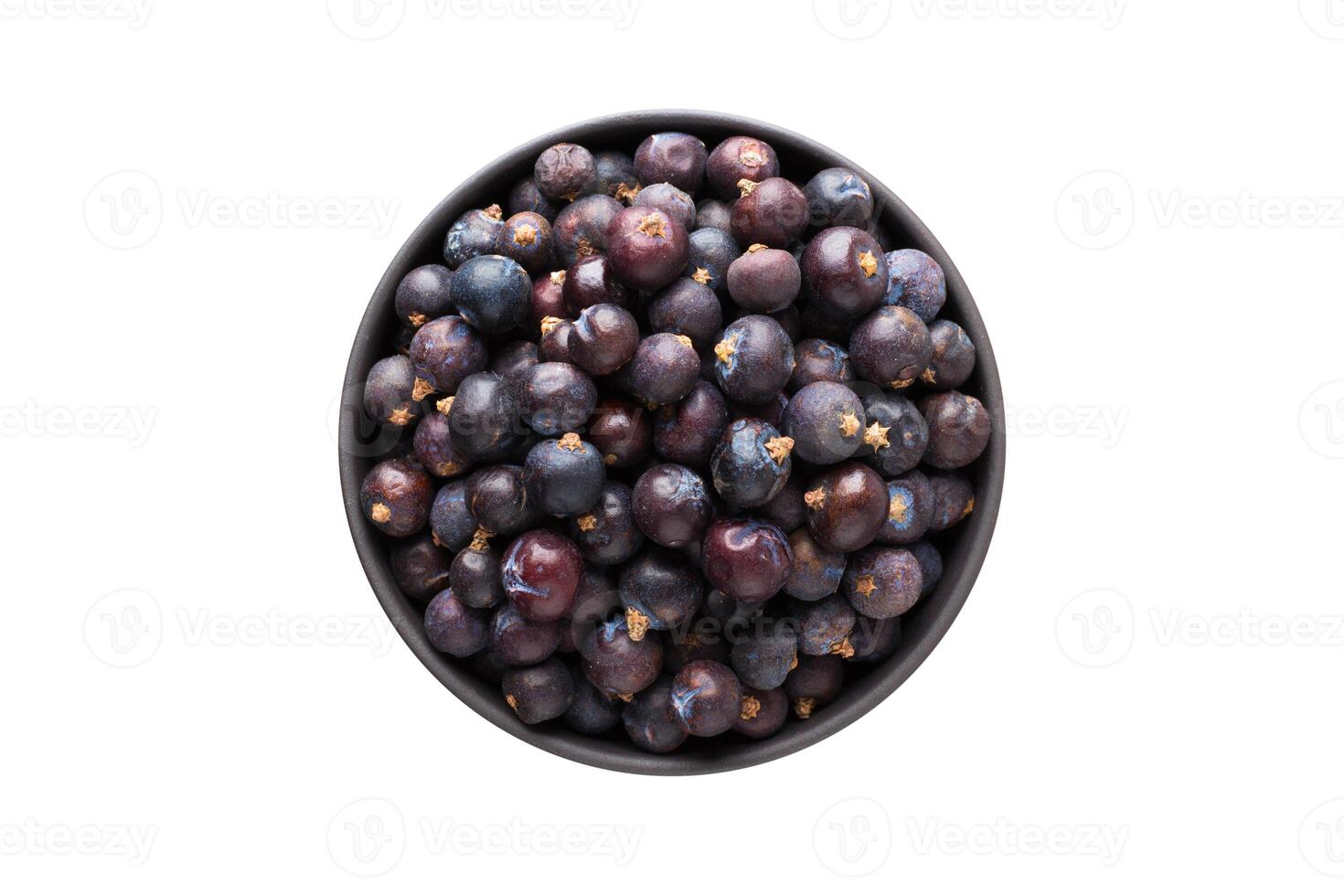 dried juniper berries in clay bowl isolated on white background. Seasoning or spice top view photo