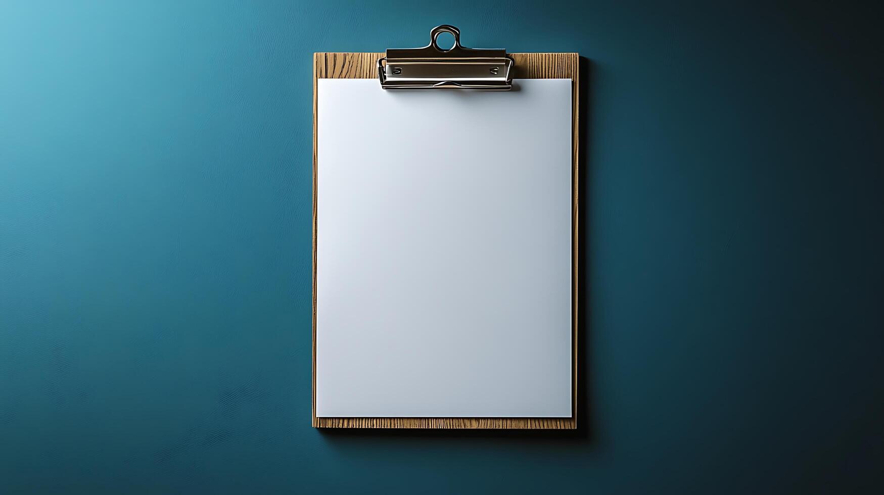 A clean clipboard with a blank white sheet of paper, ready for your text or design. This simple and versatile office supply is presented against a textured teal background. photo