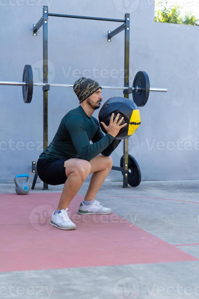 Athlete doing squats with medicine ball during outdoor workout photo