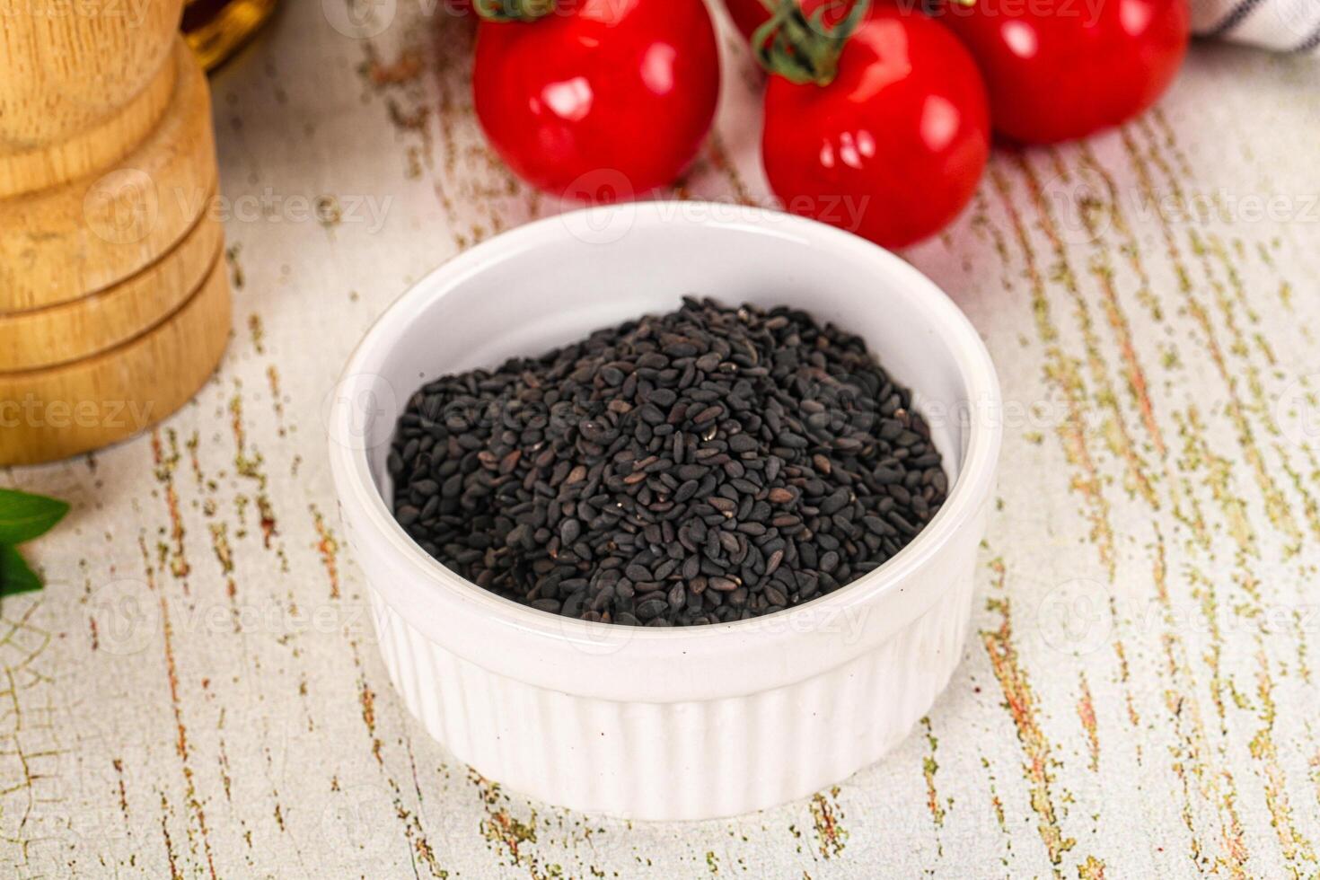 Black cumin seeds in a white bowl on a wooden table photo