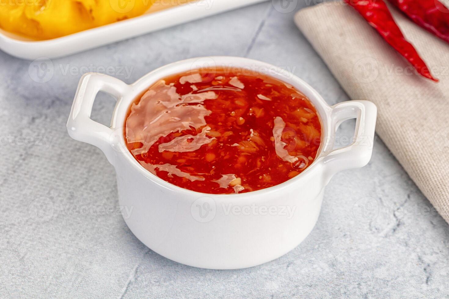 A bowl of sauce with peppers and a spoon photo