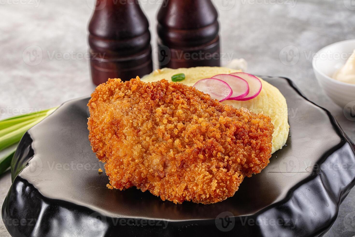 A piece of fried chicken on a black plate photo