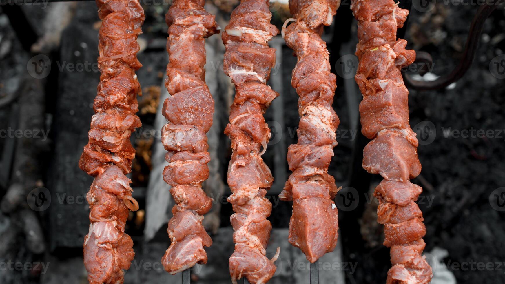 A bunch of meat on skewers on a grill photo