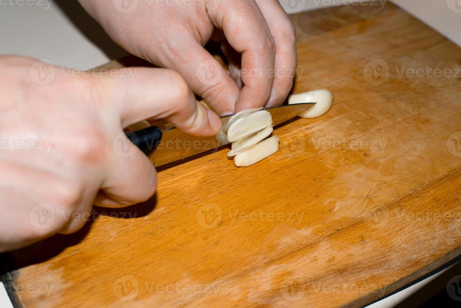 A person cutting up a piece of cheese with a knife photo