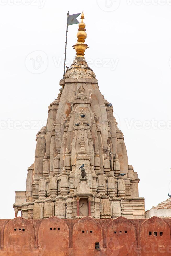 Ancient shikhara temple tower rising above red wall in Jaipur, India photo