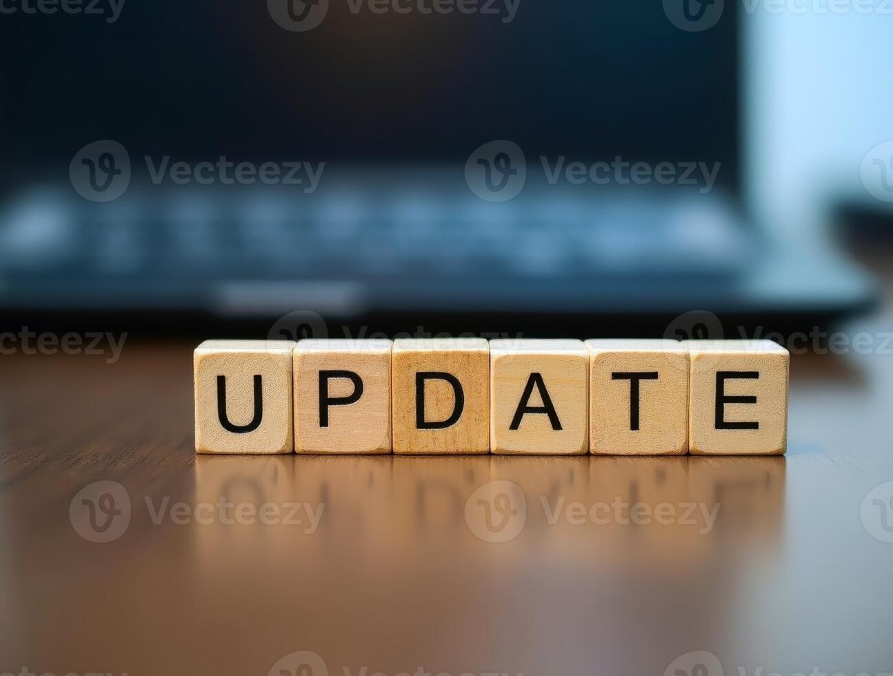 Wooden cubes showing update on a shiny surface with laptop background photo