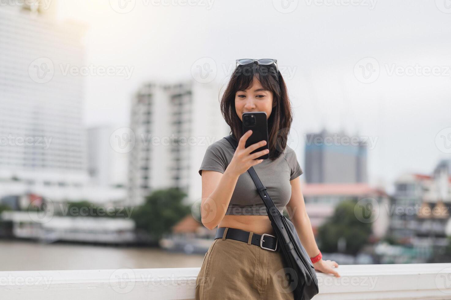 Happy young southeast asian woman teenager blogger using smartphone searching tourism guide. World travel explorer Asia concept for local cultural experience near Chao Phraya River Bangkok photo