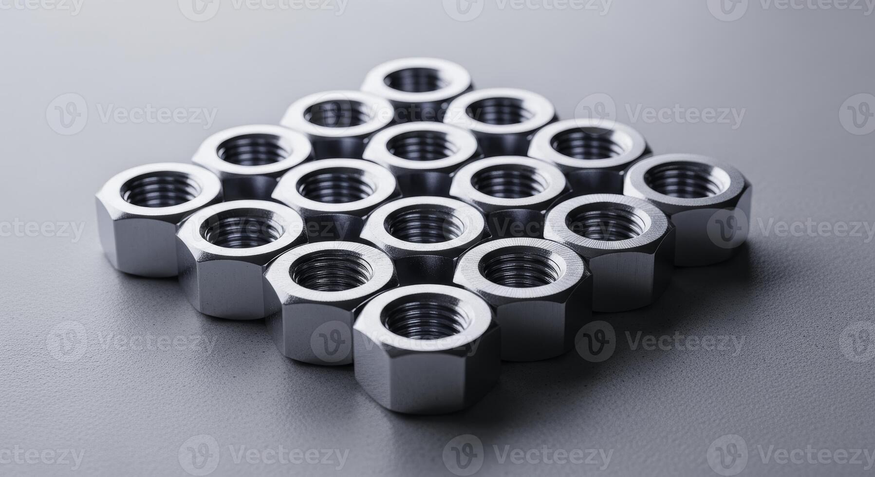 Shiny metal hexagonal nuts arranged in a geometric pattern on gray background photo