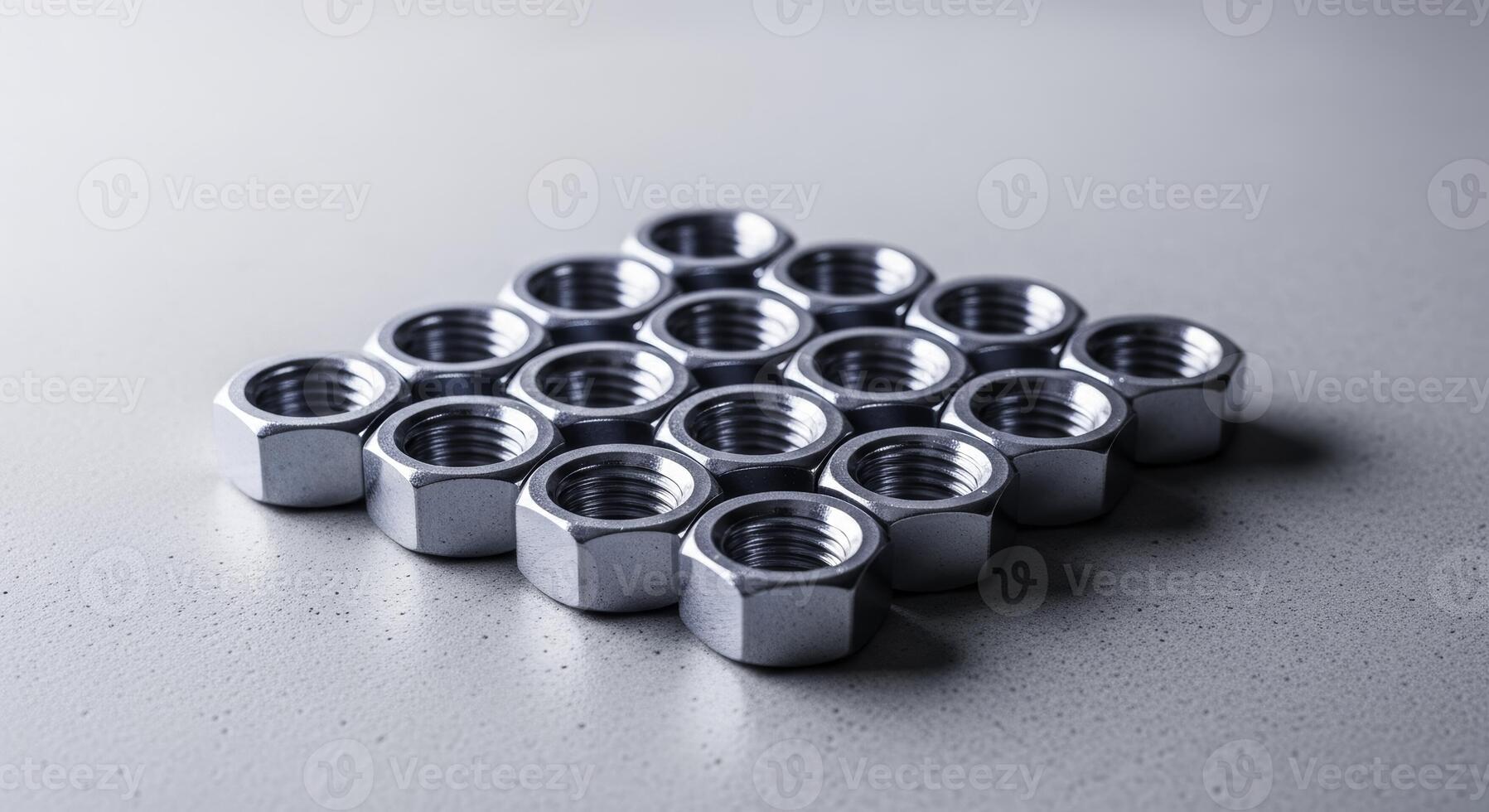 Shiny metal hexagonal nuts neatly arranged in a pattern on a light surface photo