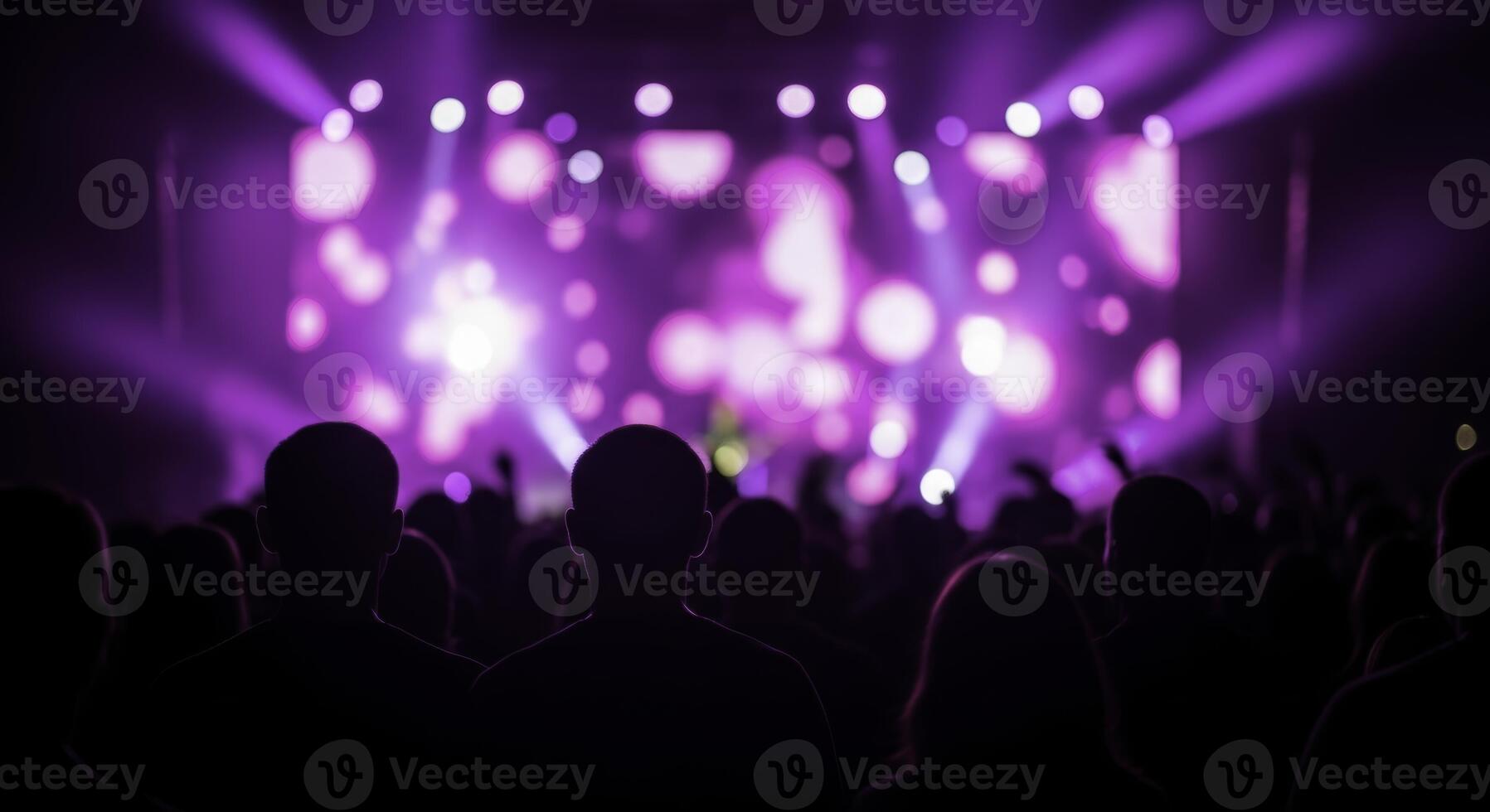 Silhouetted crowd enjoying live music concert with vibrant purple stage lights photo