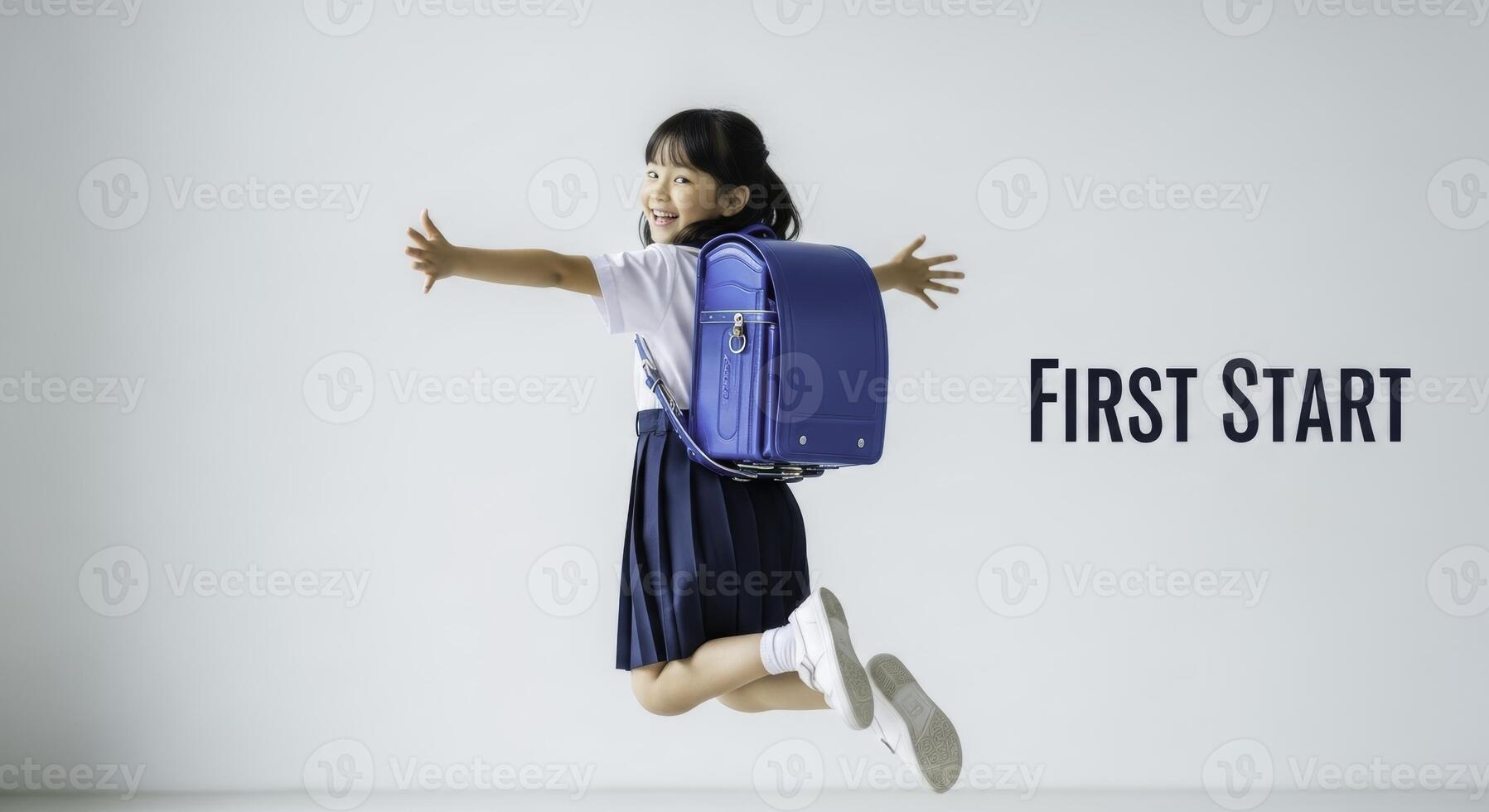 Excited asian elementary school girl in uniform and randoseru backpack jumping with joy photo