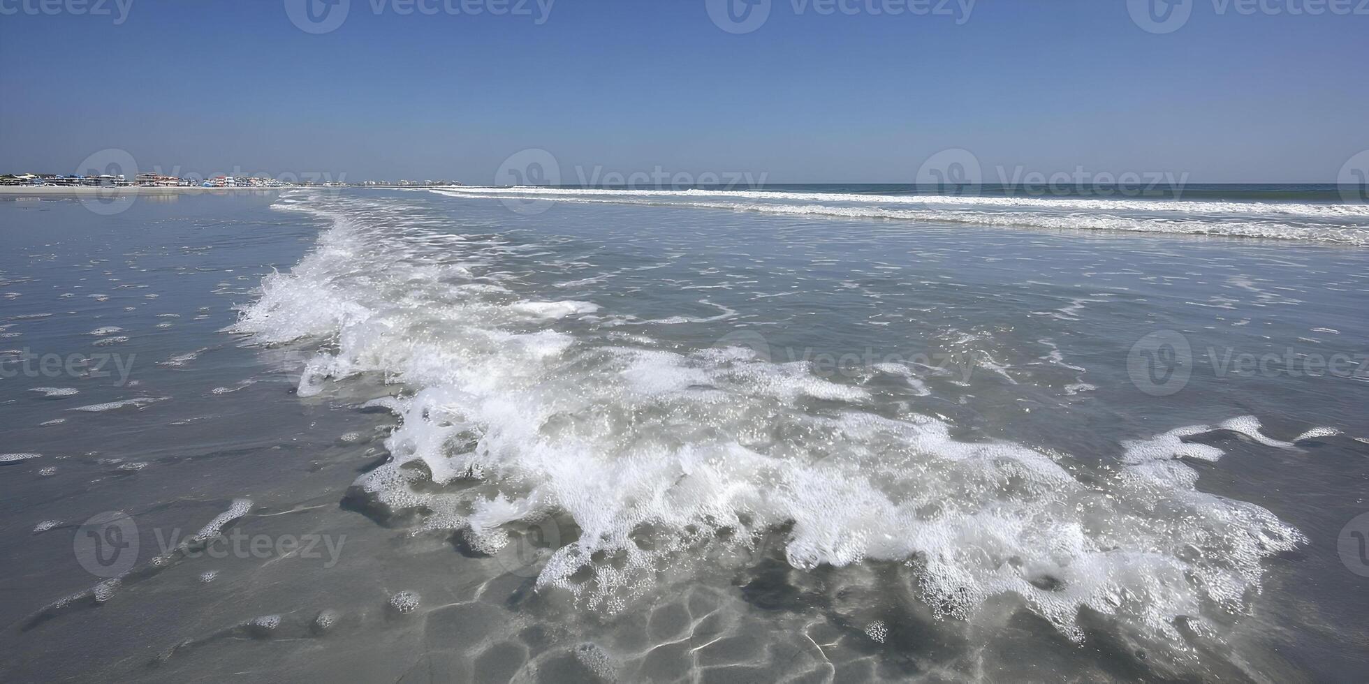 Ocean Wave Crashing on Sandy Beach Shoreline Buildings in Background Sunny Day Seascape photo
