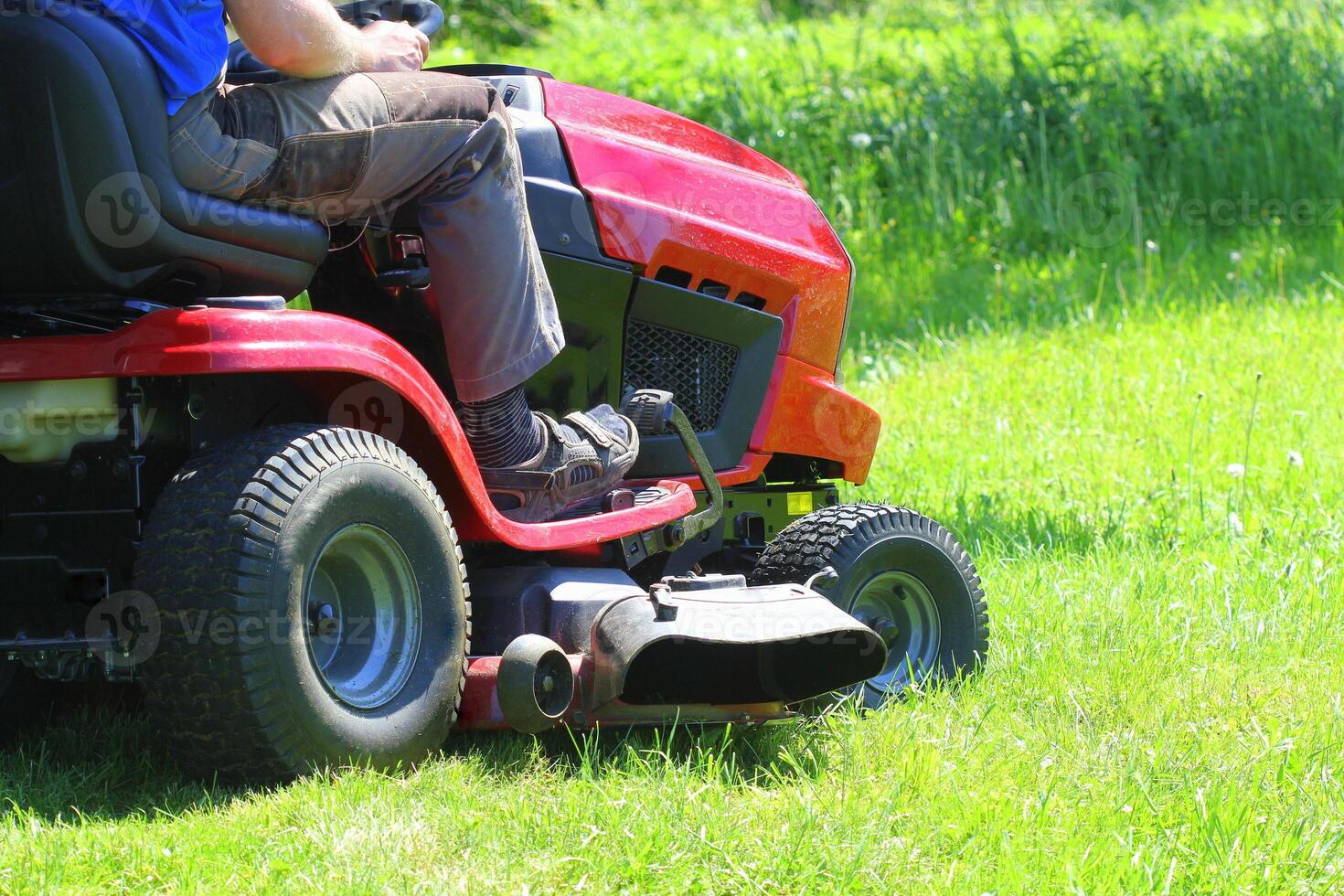 Gardener driving a riding lawn mower in a garden photo