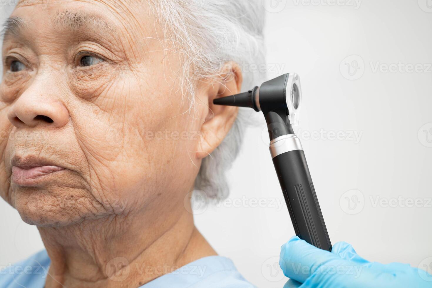 Otolaryngologist ENT physician doctor examining senior patient ear with otoscope, hearing loss photo