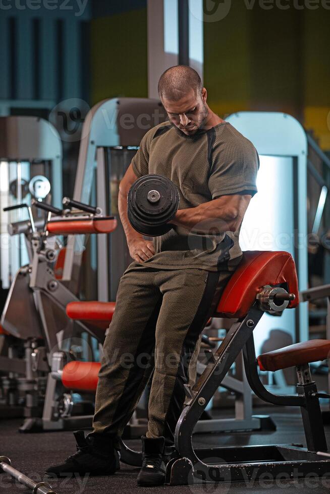 Male athlete lifting a dumbbell in a gym during strength training session photo