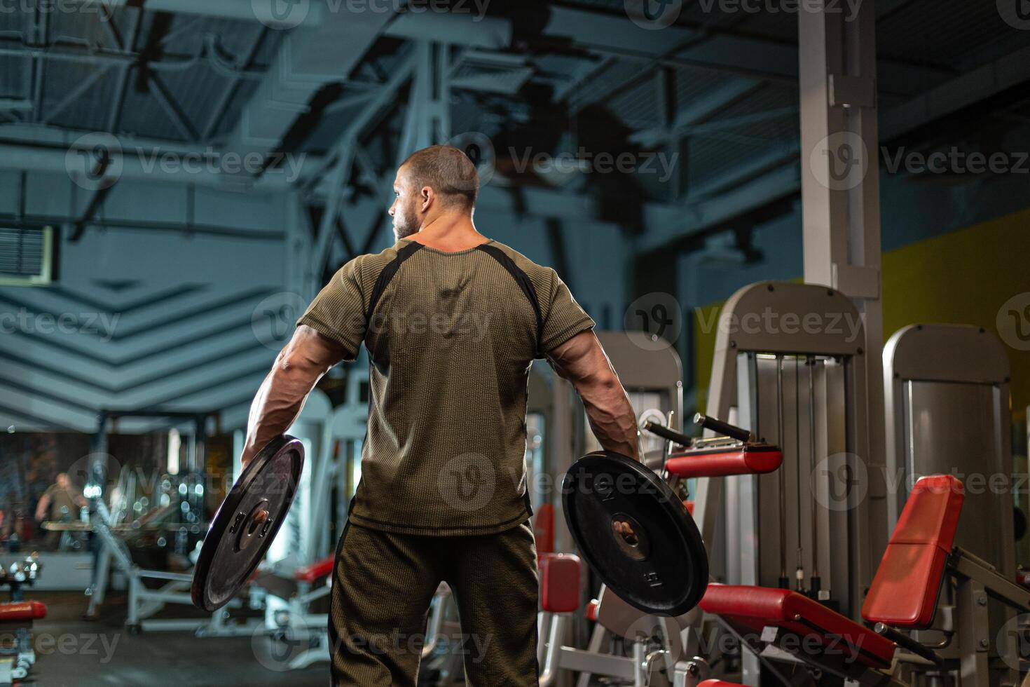 Male athlete performing weight training in a modern gym environment during evening workout session focused on strength building photo