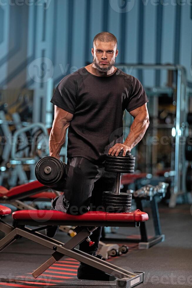 Muscular male athlete performing strength training in a modern gym during evening hours photo