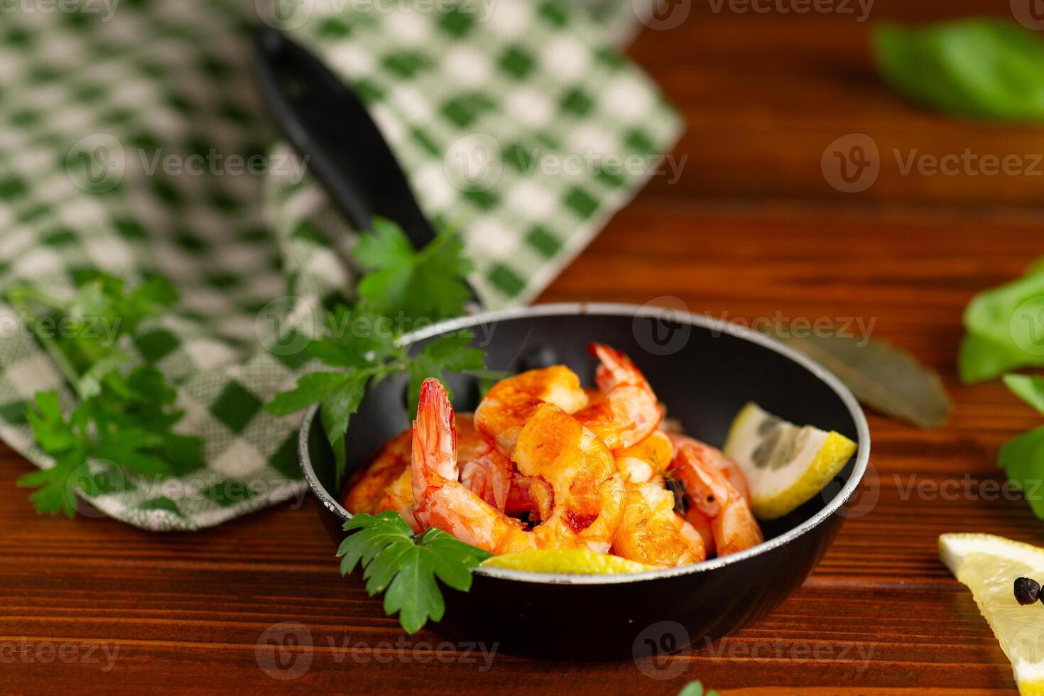 Culinary process of cooking shrimps in a frying pan with lemon on a wooden photo