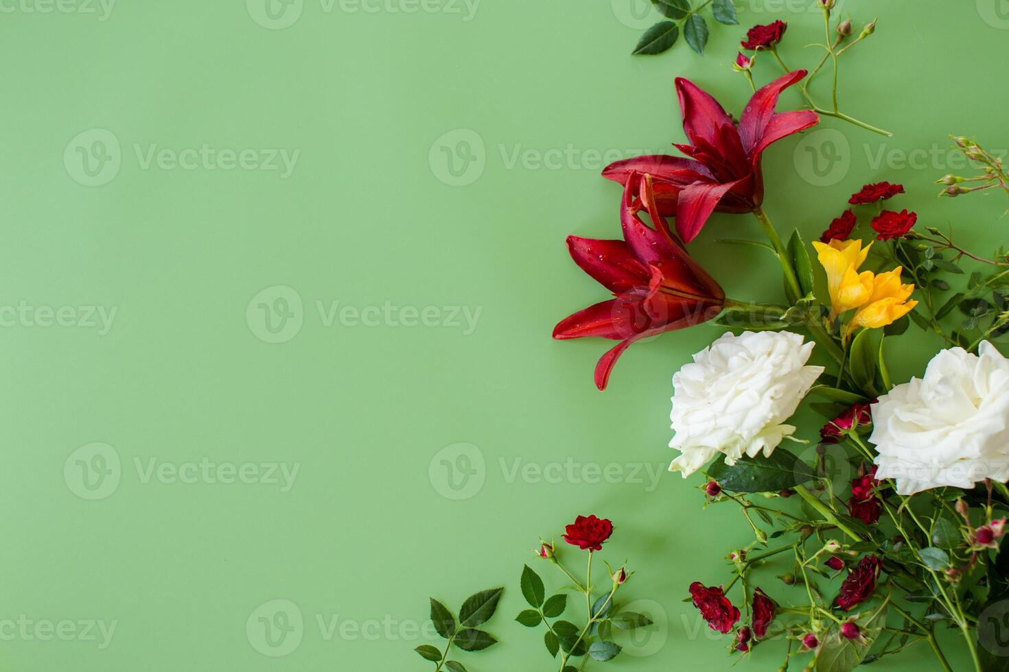 Detailed view of two large red lilies with red and white roses on a green background photo