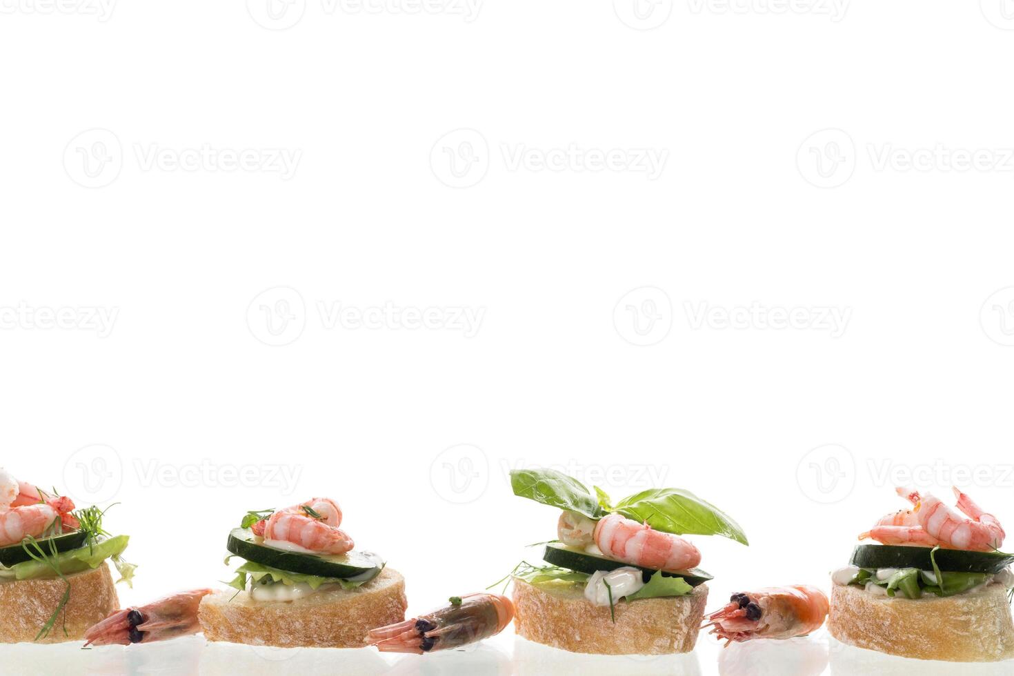 Minimalistic canapes with shrimps, salad and cucumber on a white background photo
