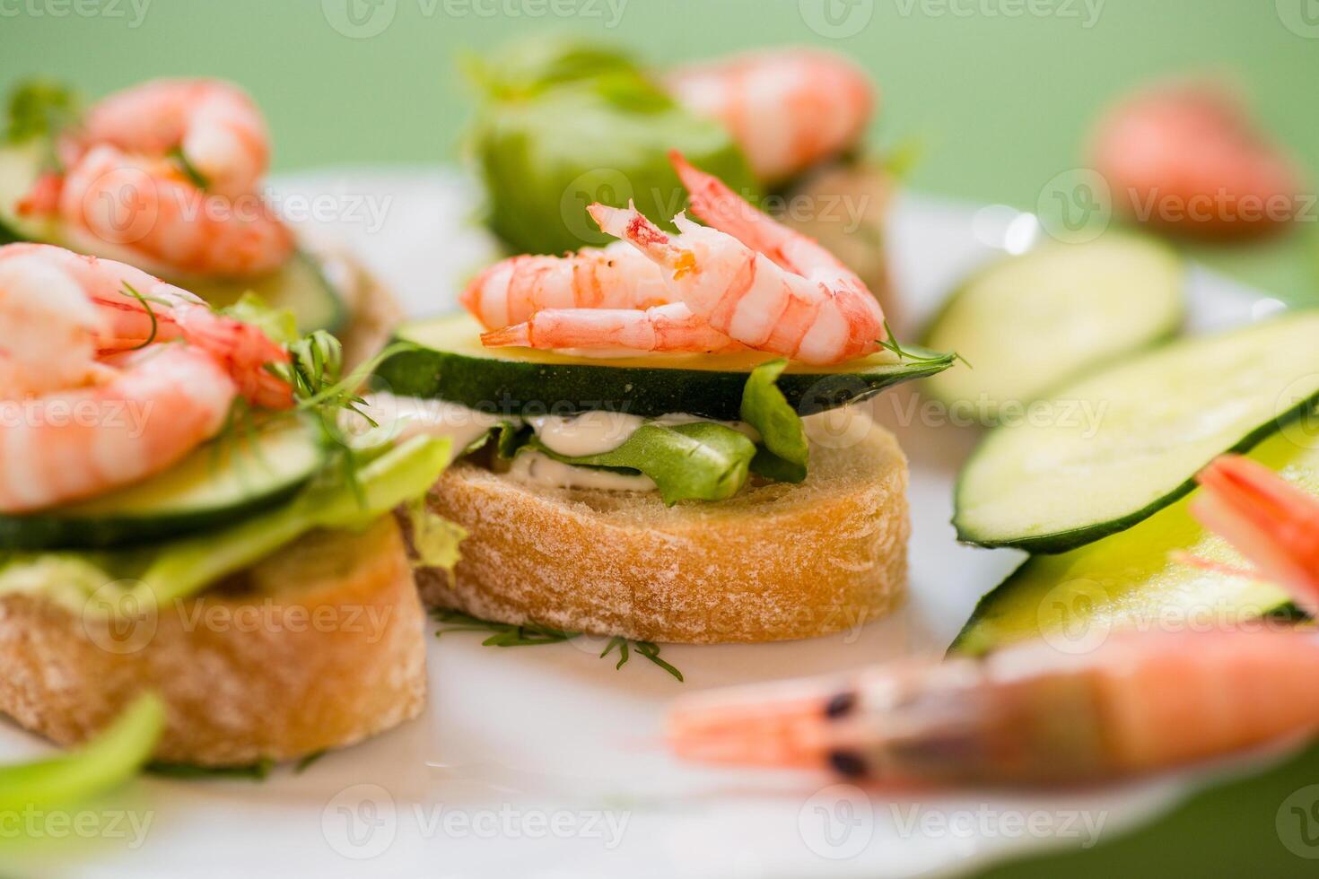 Appetizing appetizers with shrimps, sauce and cucumbers on a green background photo