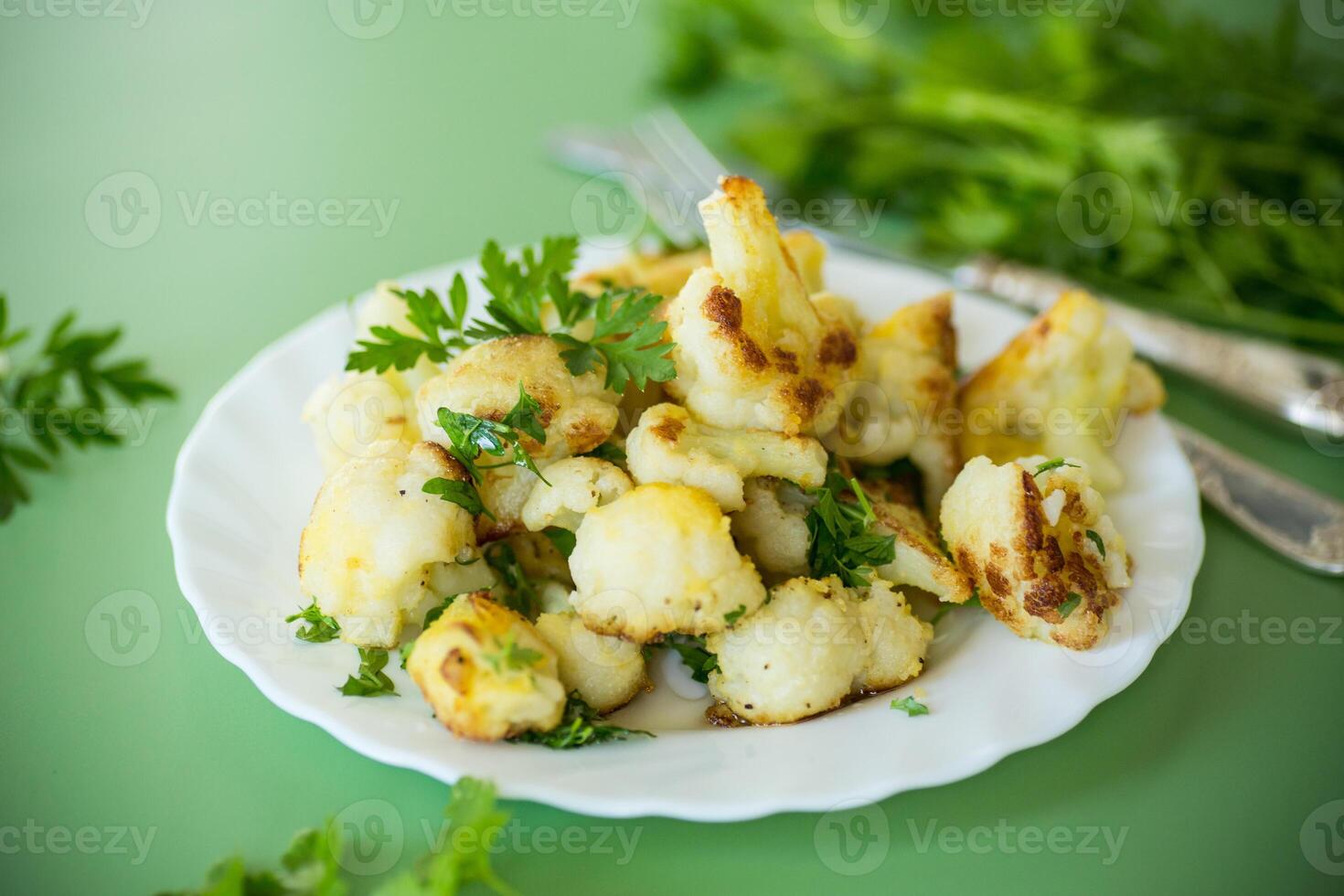 Fried cauliflower with spices and herbs on a green background photo