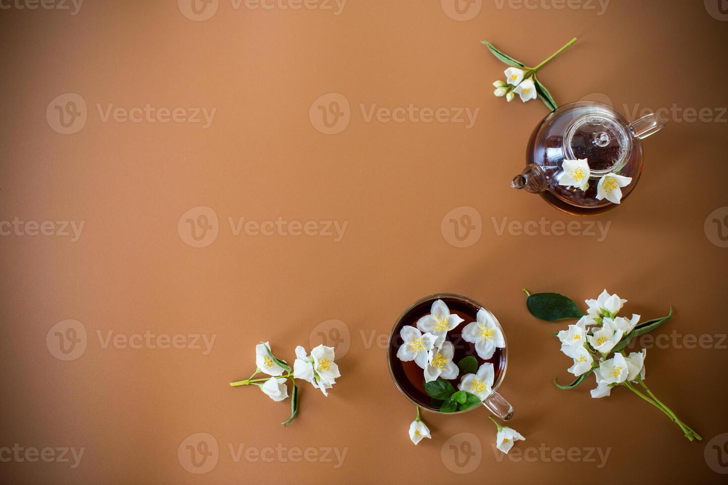 Tea composition with green tea and jasmine flowers on a brown background photo