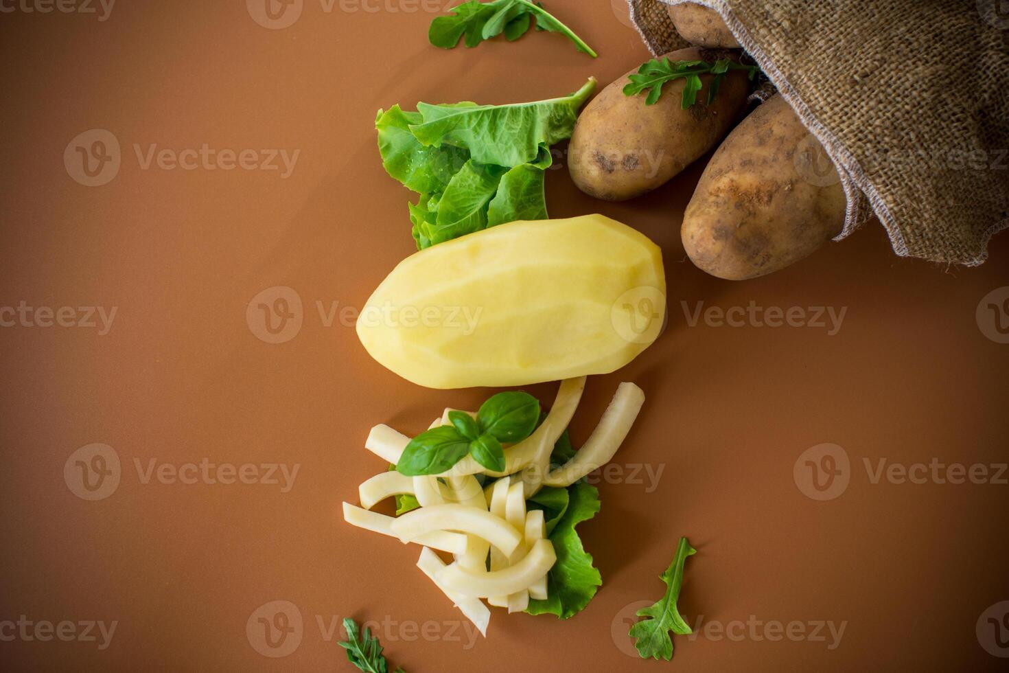 Nutritious potatoes whole, peeled and sliced on a brown background photo