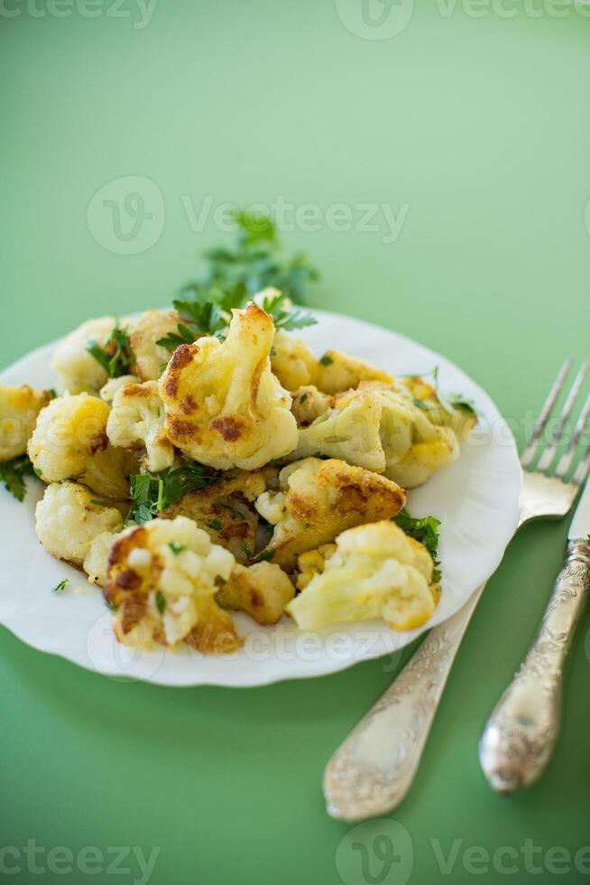 Fried cauliflower with spices and herbs on a green background . photo