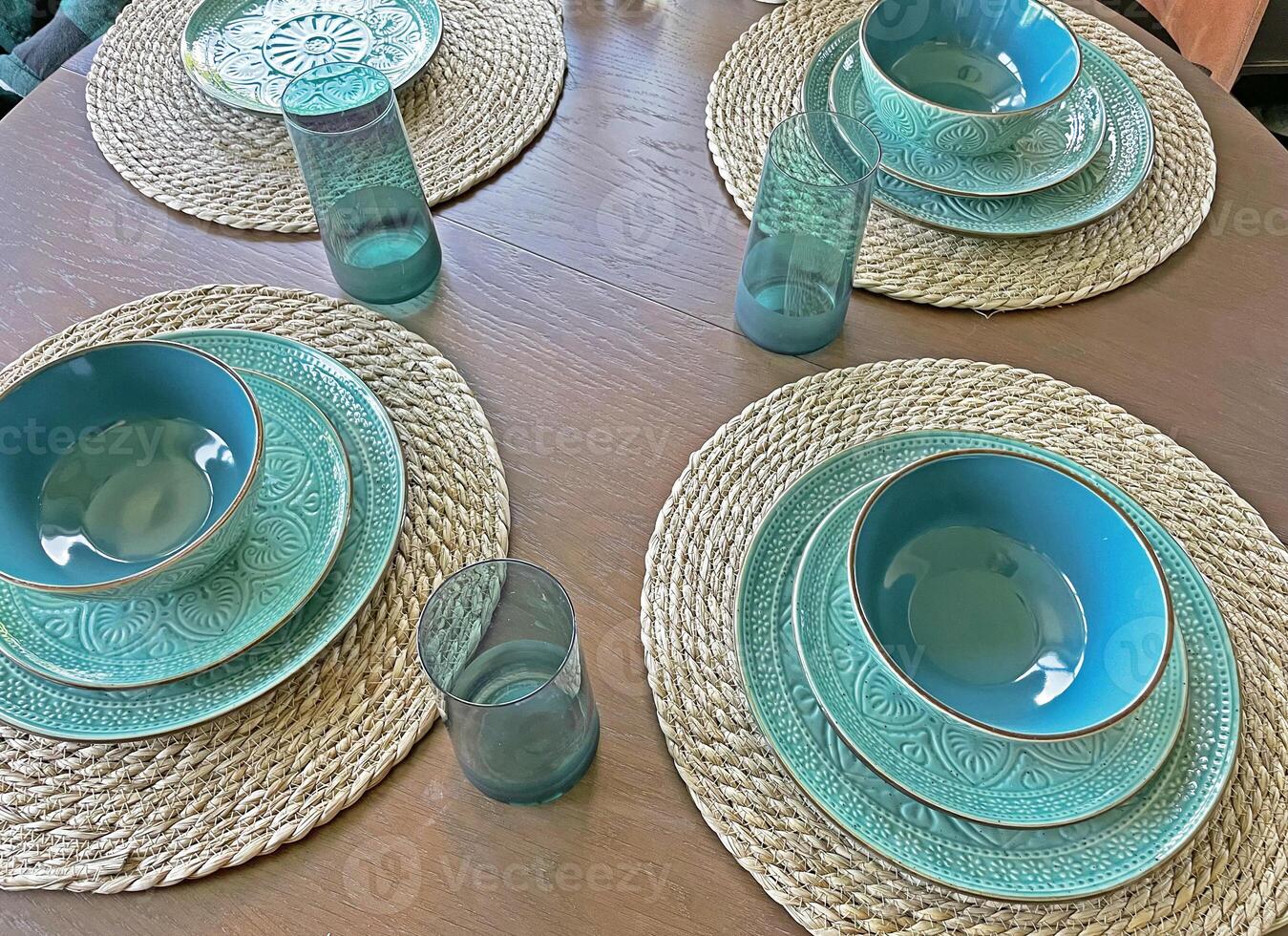Blue dishes on table, plates and glasses, plates on wicker coasters, top view photo