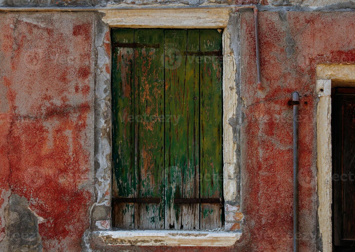 Rustic green shutter on weathered red wall with rustic textures photo