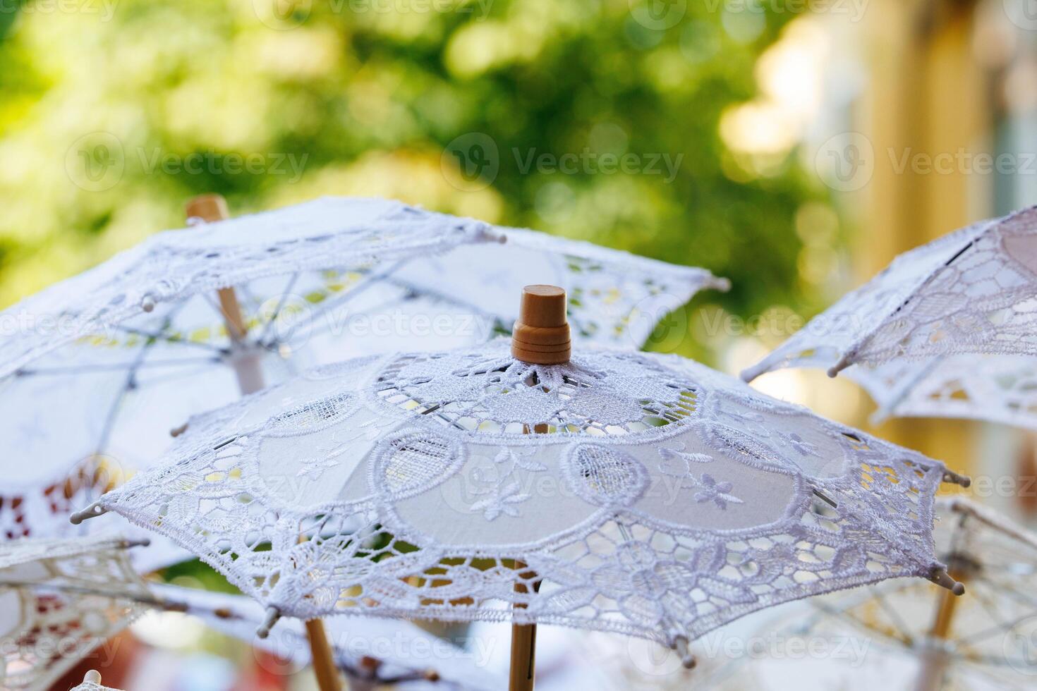 Delicate lace parasols against vibrant greenery photo