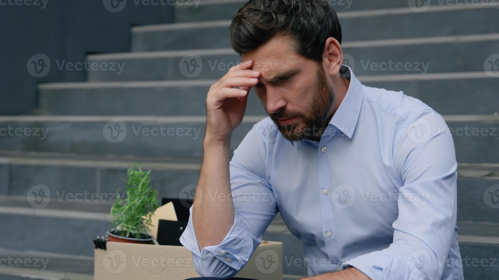 Close up depressed Caucasian middle aged business man lost job pensive holding head frustrated emotion sitting stairs near office building with dismissal box businessman male suffering unemployment photo